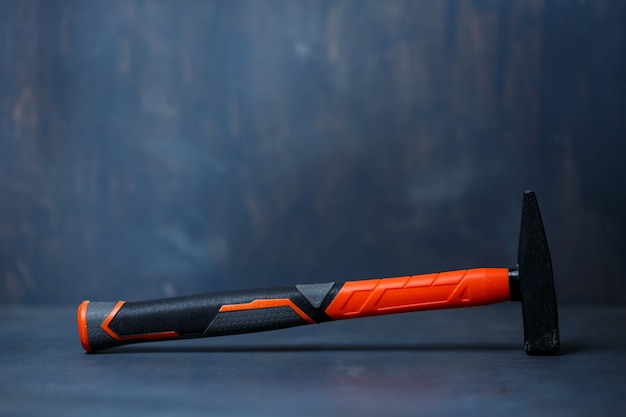 Ein kleiner Hammer in Schwarz und Orange auf grauem Hintergrund.