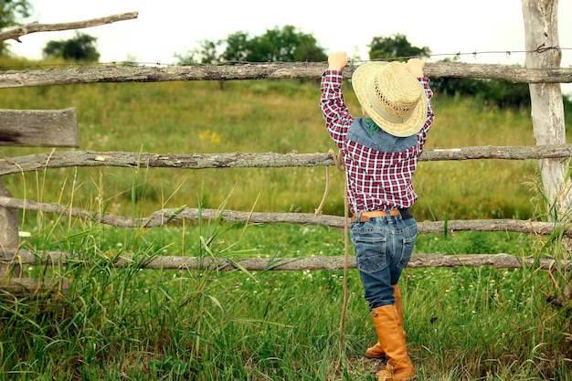 Ein kleiner Junge Cowboy mit Hut in der Nähe von Zaun auf Natur