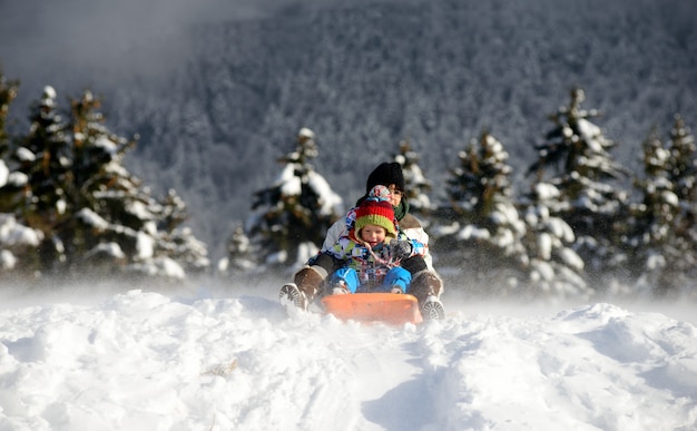 Ein kleiner Junge, der im Schnee rodelt