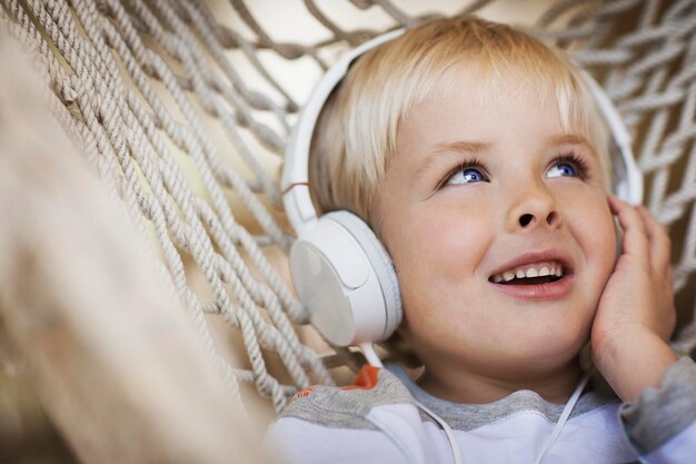 Foto ein kleiner junge, der in einer hängematte liegt und musikkopfhörer trägt