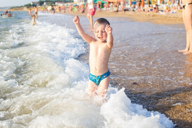 Ein kleiner Junge, der Spaß im Meer auf den Wellen hat