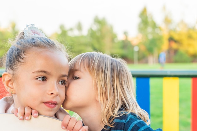 Ein kleiner Junge flüstert seiner kleinen Schwester etwas zu