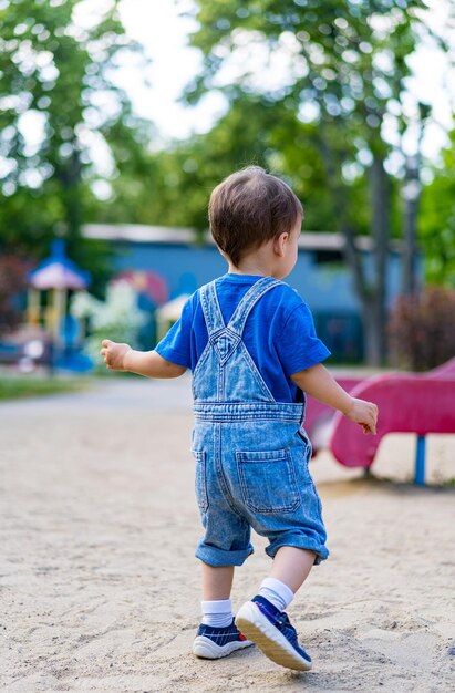 Ein kleiner Junge geht an einem sonnigen Tag im Park spazieren