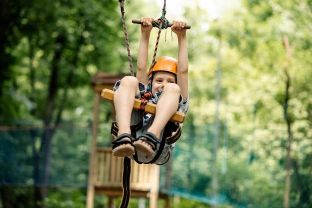 Ein kleiner Junge hängt an der Leine im Seilpark Sportunterhaltung für eine aktive Erholung des Kindes