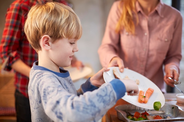 Ein kleiner Junge hilft beim Abräumen der Teller nach dem Essen in einer Familienküche