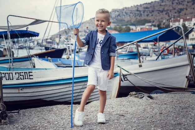 Ein kleiner Junge im Marinestil vor dem Hintergrund von Booten und Yachten. Idee und Konzept Freundschaft, Urlaub, Urlaub, Familie