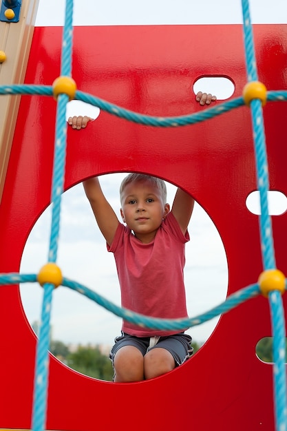 Ein kleiner Junge in einem roten T-Shirt auf dem Spielplatz