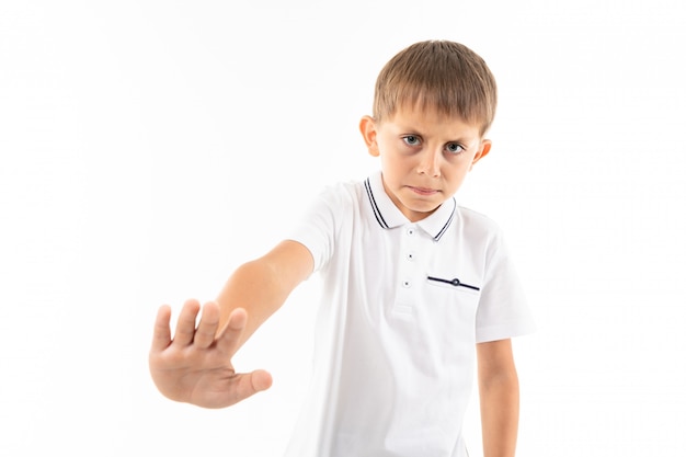 Ein kleiner Junge in einem weißen Hemd, blauen Shorts mit blonden Haaren, weißes T-Shirt zeigt "Stop"