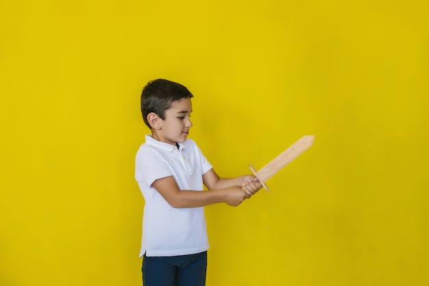 ein kleiner Junge in einem weißen Hemd steht an einer gelben Wand.