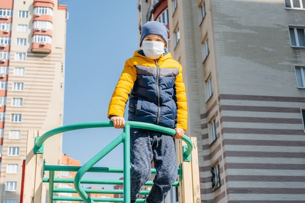 Ein kleiner Junge in einer Maske geht während der Quarantäne auf den Spielplatz. Bleib zuhause.