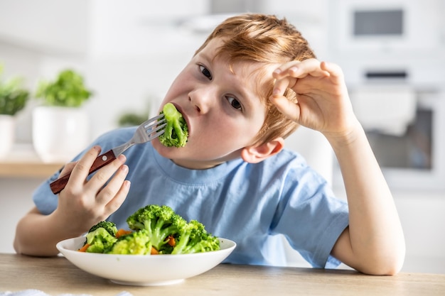 Ein kleiner Junge isst Brokkoli zum Mittagessen.
