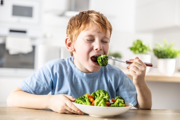 Ein kleiner Junge isst Brokkoli zum Mittagessen.