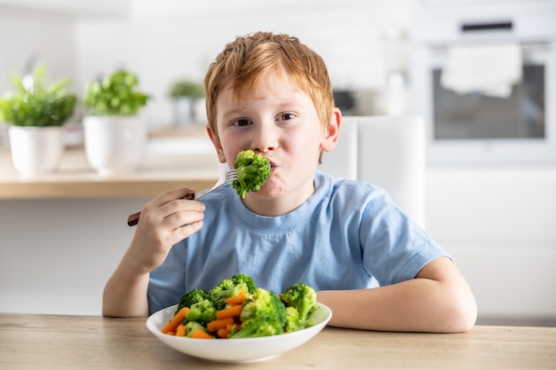 Ein kleiner Junge isst Brokkoli zum Mittagessen.
