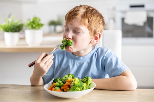Ein kleiner Junge isst Brokkoli zum Mittagessen.