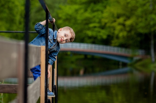 Ein kleiner Junge klettert im Park auf ein Brückengeländer Die Gefahr des Ertrinkens Gefahr für Kinder