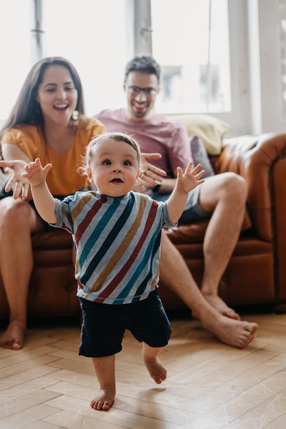 Foto ein kleiner junge läuft, während seine eltern zu hause auf dem sofa sitzen