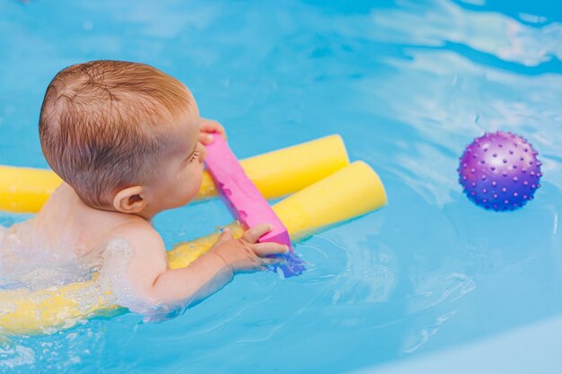 Ein kleiner Junge lernt im Babybecken schwimmen. Entwicklung der Kinder Erster Schwimmunterricht für Kinder