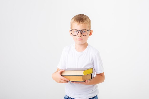 Ein kleiner Junge mit Brille hält einen Stapel Bücher auf weißem Hintergrund isoliert