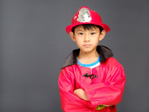 Ein kleiner Junge mit Feuerwehrmütze und blauem Hemd.