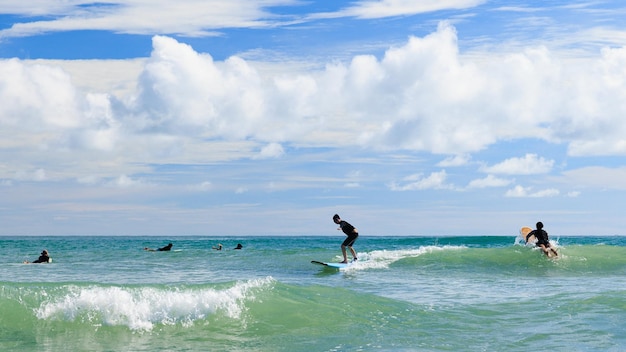 Ein kleiner Junge mit Schwimmbrille steht auf einem Softboard und übt das Surfen in einem Anfängerkurs