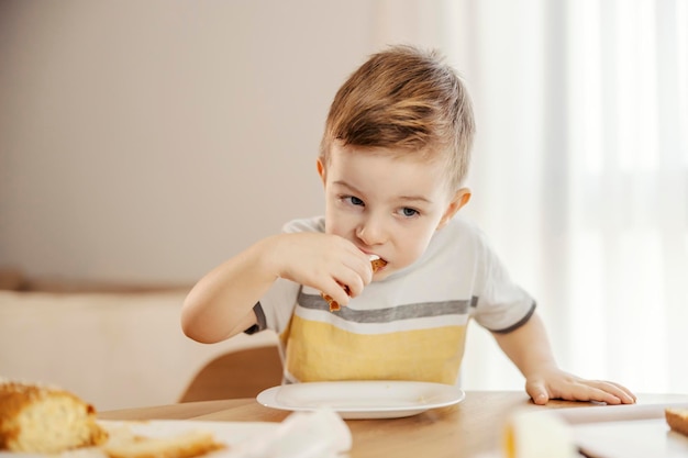 Ein kleiner Junge sitzt am Esstisch und frühstückt