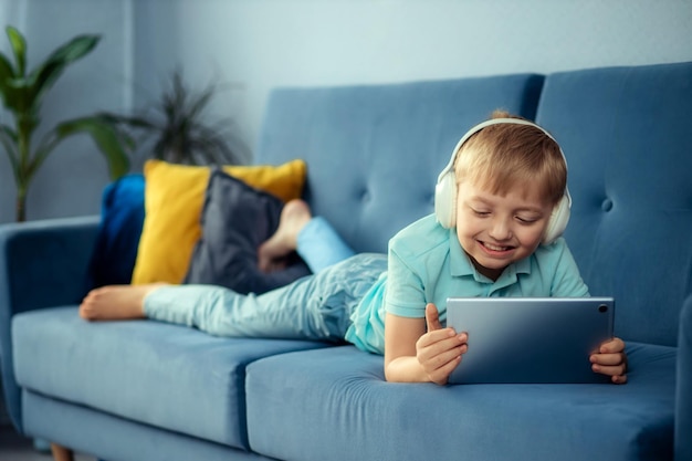 Foto ein kleiner junge sitzt auf einem sofa und spielt ein spiel auf einem digitalen tablet und schaut sich zeichentrickfilme an