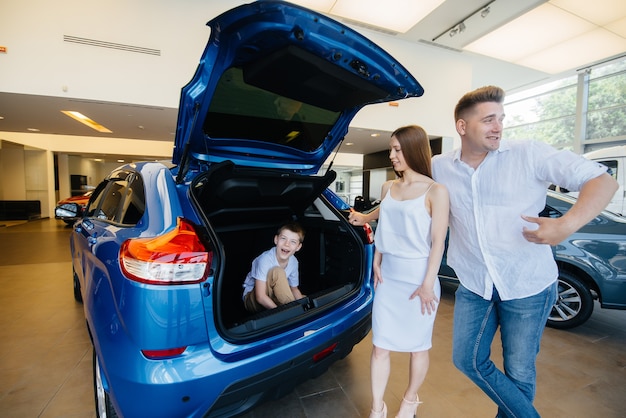 Ein kleiner Junge sitzt im Kofferraum, während seine Eltern sich ein neues Auto aussuchen.