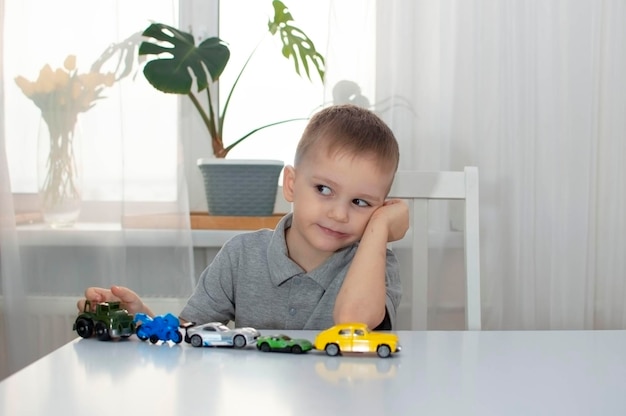 Ein kleiner Junge spielt gerne mit bunten Autos an einem großen Tisch, lacht und genießt sein Spielzeug