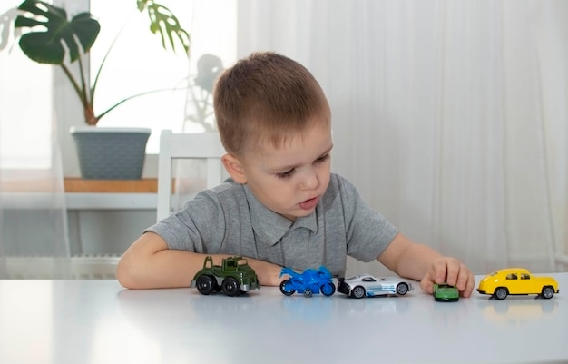 Ein kleiner Junge spielt gerne mit bunten Autos an einem großen Tisch, lacht und genießt sein Spielzeug