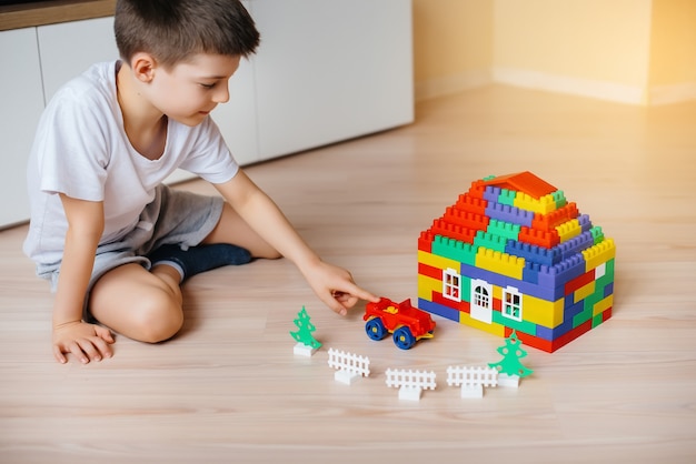 Ein kleiner Junge spielt mit einem Baukasten und baut ein großes Haus für die ganze Familie