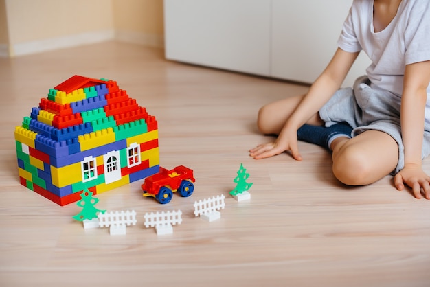 Ein kleiner Junge spielt mit einem Bausatz und baut ein großes Haus für die ganze Familie. Bau eines Einfamilienhauses.