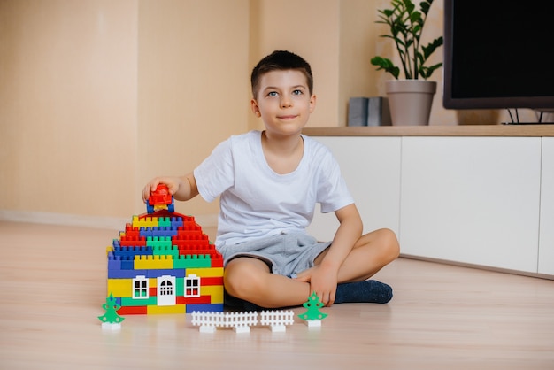 Ein kleiner Junge spielt mit einem Bausatz und baut ein großes Haus für die ganze Familie. Bau eines Einfamilienhauses.