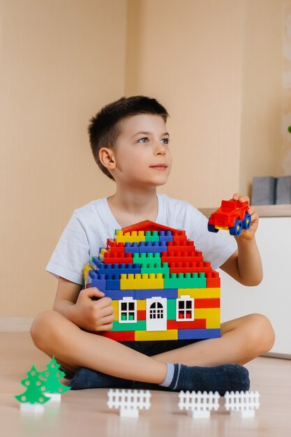 Ein kleiner Junge spielt mit einem Bausatz und baut ein großes Haus für die ganze Familie. Bau eines Einfamilienhauses.