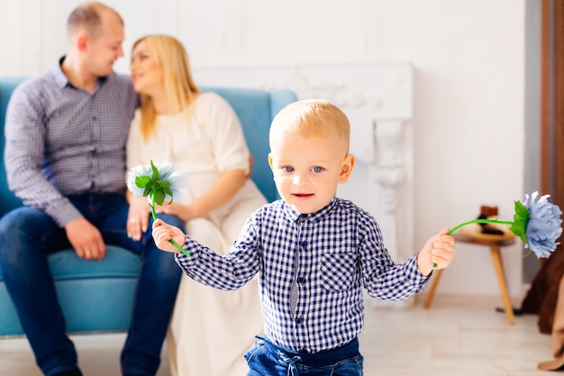 Ein kleiner Junge spielte mit den Eltern dahinter mit Blumen