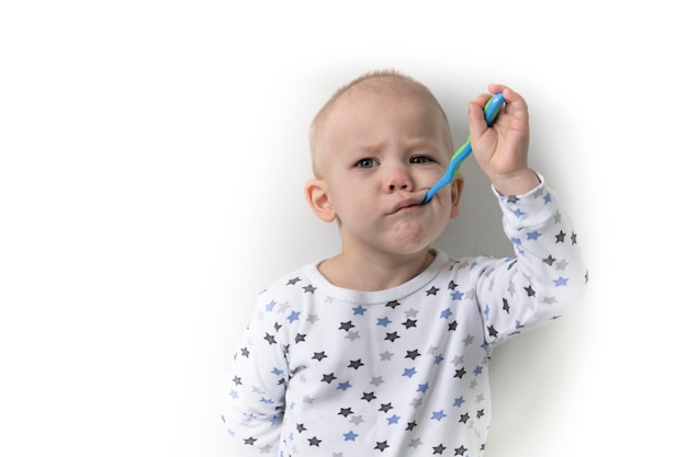Ein kleiner Junge steht in einem T-Shirt mit Sternen, putzt sich die Zähne und kümmert sich um seinen Mund