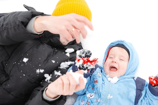 Ein kleiner Junge und sein Vater spielen im Winter Outdoor-Erholung einer Familie mit Kindern im Winter Ein Kind auf einem Spaziergang in einem schneebedeckten Winterpark