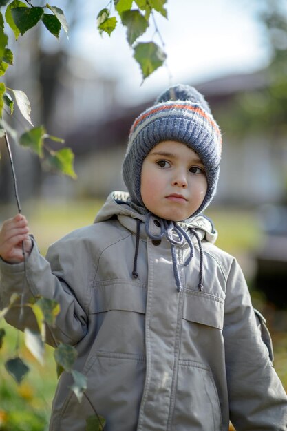 Ein kleiner Junge von 3 Jahren im Park unter den Zweigen eines Baumes