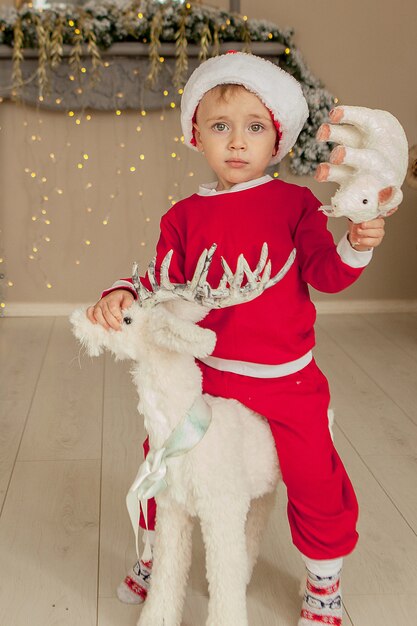 Ein kleiner Junge wartet auf Weihnachten und hat Spaß. der junge reitet zu weihnachten ein spielzeughirsch