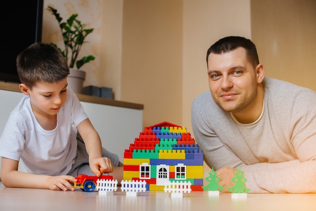 Ein kleiner Junge wird zusammen mit seinem Vater von einem Bauunternehmer gespielt und baut ein Haus. Bau eines Einfamilienhauses.