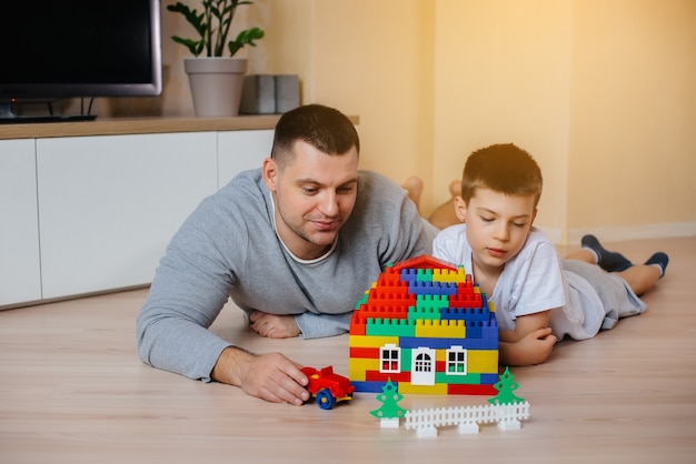 Ein kleiner Junge wird zusammen mit seinem Vater von einem Bauunternehmer gespielt und baut ein Haus