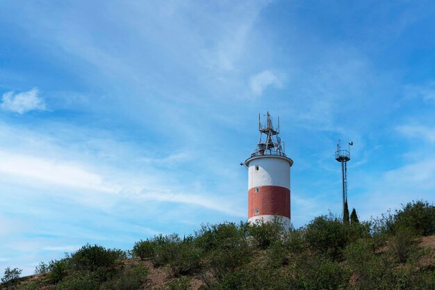 Ein kleiner Leuchtturm, der auf einem Felsen gegen den blauen Himmel steht. Foto in hoher Qualität