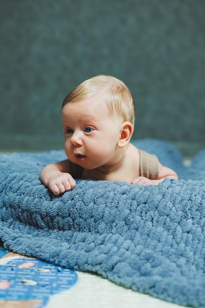 Ein kleiner neugeborener Junge liegt auf einer grauen gestrickten Decke Porträt eines einmonatigen Babys