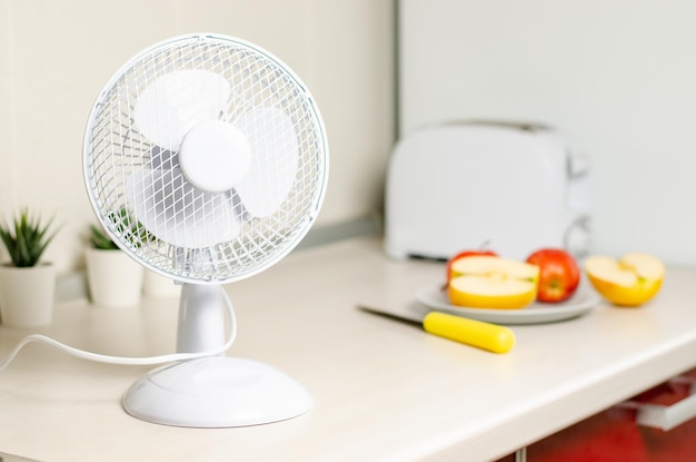 Ein kleiner Ventilator auf dem Küchentisch Das Konzept der Kühlung und Belüftung des Hauses