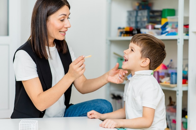 Ein kleiner Vorschuljunge ist in einem Logopädenbüro beschäftigt und korrigiert seine Sprache