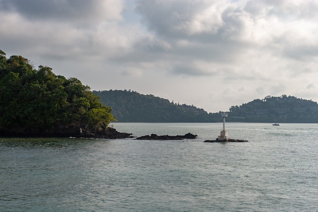 Ein kleiner weißer Leuchtturm auf den Steinen nahe der Insel am Fluss