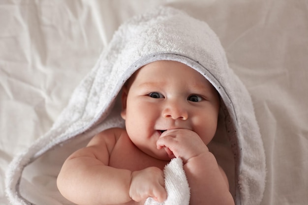 Ein kleines Baby liegt in einer HandtuchBabypflege auf dem Bett