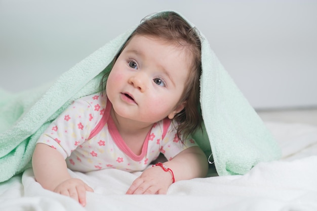 Ein kleines Baby liegt mit einem Handtuch bedeckt im Badezimmer