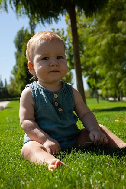 Ein kleines Baby sitzt auf dem Gras im Park und studiert die Grashalme spielt mit dem GrasSommer und die strahlende SonneEin Spaziergang an der frischen Luft