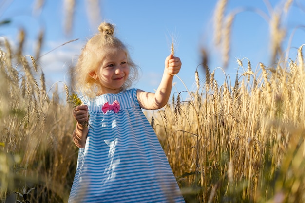 Ein kleines blondes Mädchen auf einem Roggenfeld, ein glückliches Kind.
