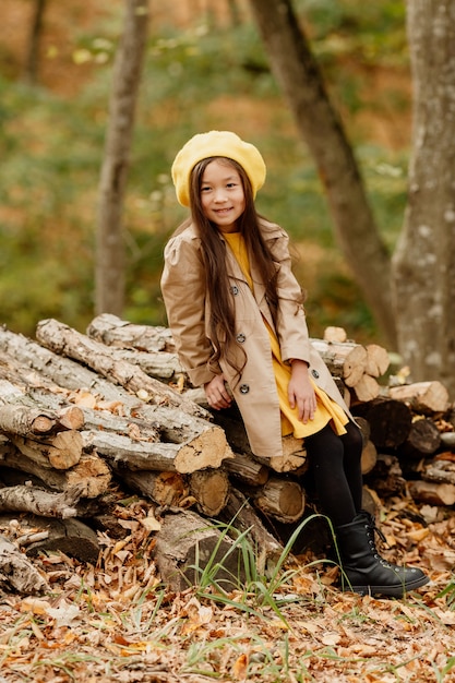 Ein kleines brünettes asiatisches Mädchen in Herbstkleidung geht im Herbstwald in der Nähe eines Baches